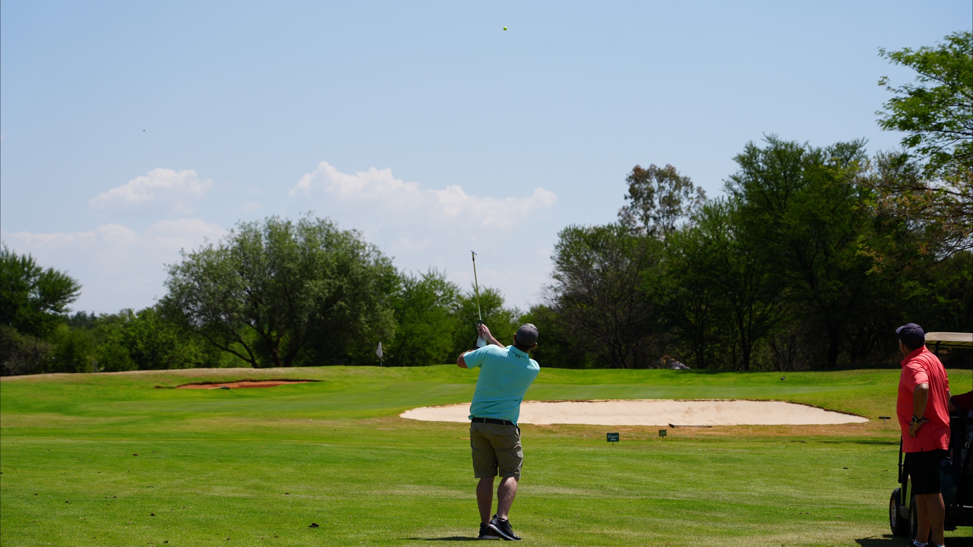 Golfer playing an approach shot into the green